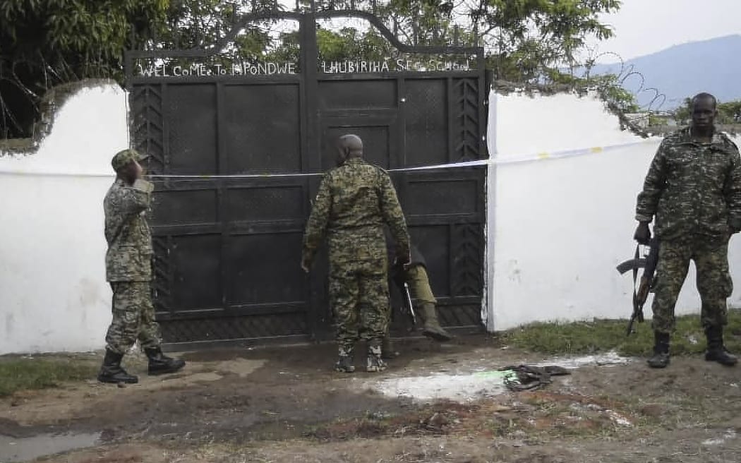 Uganda security forces are seen standing at the premises of an attack in Mpondwe, Uganda, on June 17, 2023 at the Mpondwe Lhubiriha Secondary School. The death toll from an attack on a school in western Uganda by militants linked to the Islamic State group has risen to 37, the country's army spokesman said Saturday. (Photo by AFP)