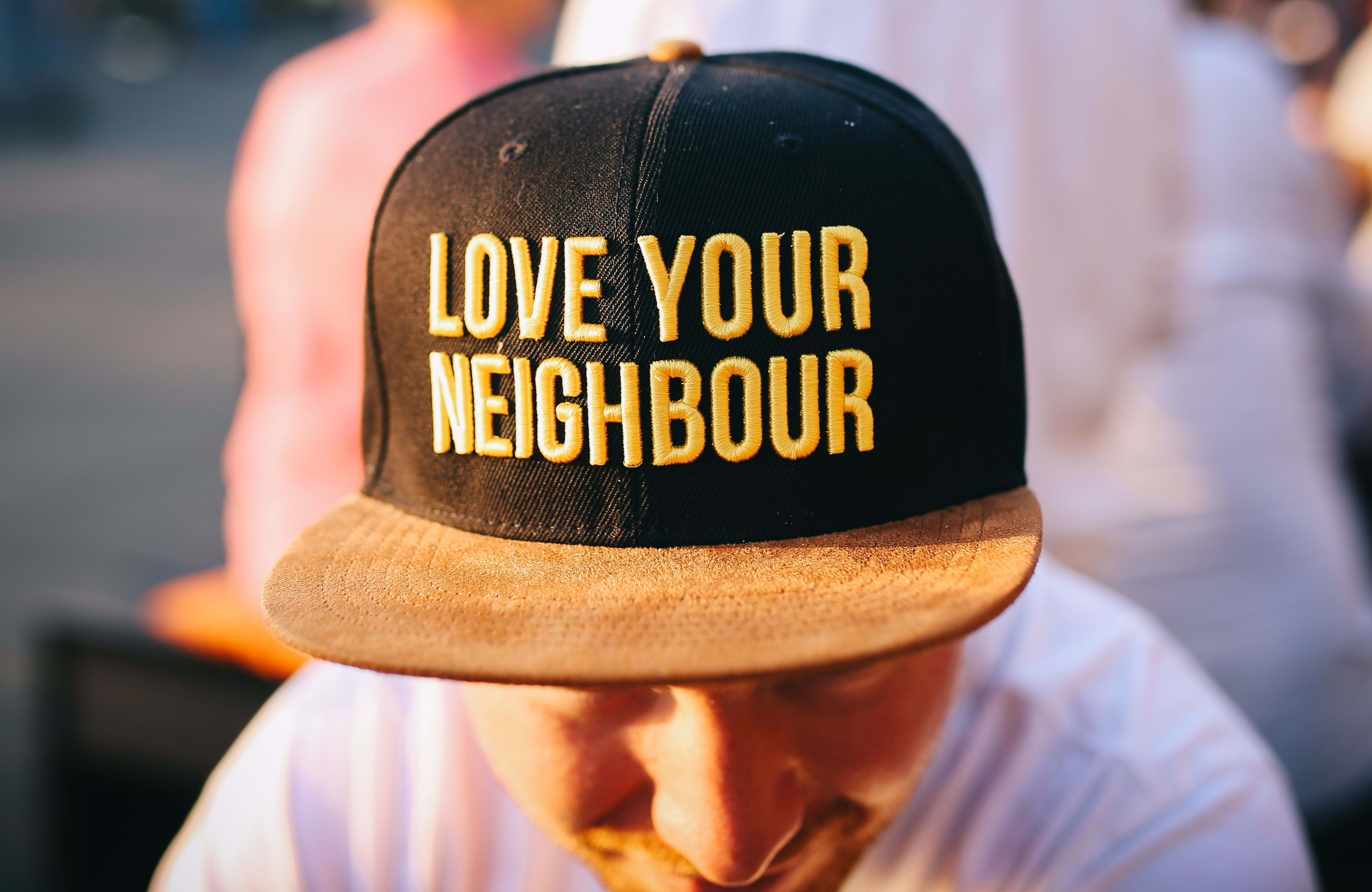 man in 'love your neighbour' cap
