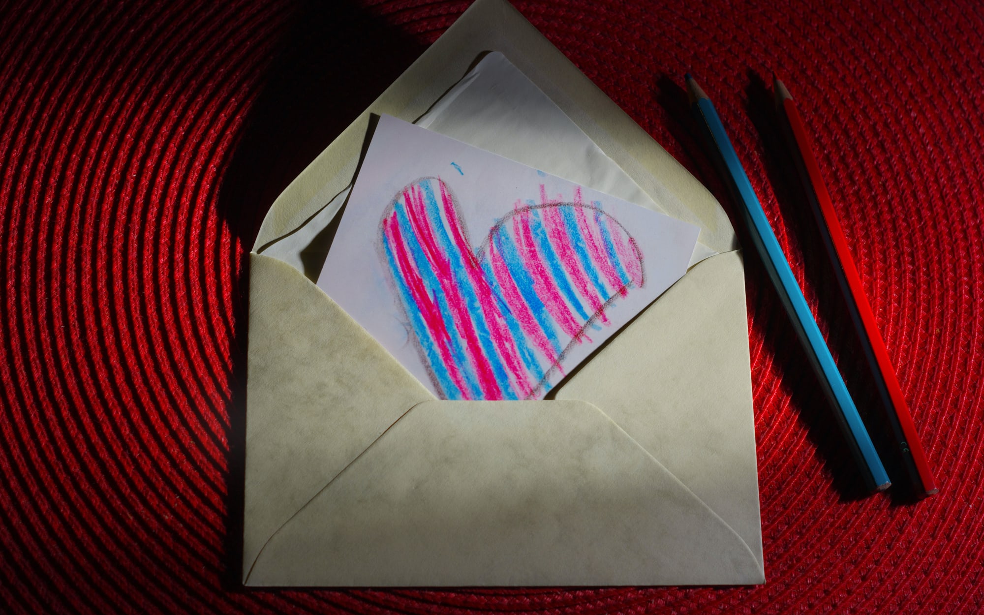 A handwritten card with a heart drawn on it, stuffed into a brown envelope.