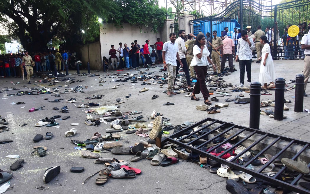 Fans stand next to abandonned shoes and a fallen barrier following a stampede during celebrations, a day after Royal Challengers Bengaluru's victory at the Indian Premier League (IPL) Twenty20 final cricket match, outside the M. Chinnaswamy Stadium in Bengaluru on June 4, 2025. At least 11 people were killed in a stampede on June 4, as a tightly packed crowd celebrated the victory of their home cricket team in the Indian city of Bengaluru, the state's chief minister said. (Photo by AFP)