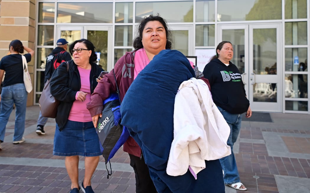 People arrive at an evacuation center in the Pasadena Convention Center in Pasadena, California, as they flee wildfires in the Los Angeles area on January 10, 2025. Massive wildfires that engulfed whole neighborhoods and displaced thousands in Los Angeles have killed at least 10 people, authorities said, as California's National Guard soldiers readied to hit the streets to help quell disorder.
News of the growing toll, announced late Thursday January 9 by the Los Angeles County Medical Examiner, came as swaths of the United States' second-largest city lay in ruins. (Photo by Agustin PAULLIER / AFP)