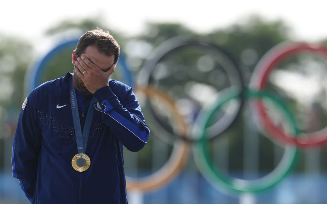 Gold medallist US' Scottie Scheffler celebrates on the podium after round 4 of the men’s golf individual stroke play of the Paris 2024 Olympic Games at Le Golf National in Guyancourt, south-west of Paris on August 4, 2024. (Photo by Emmanuel DUNAND / AFP)