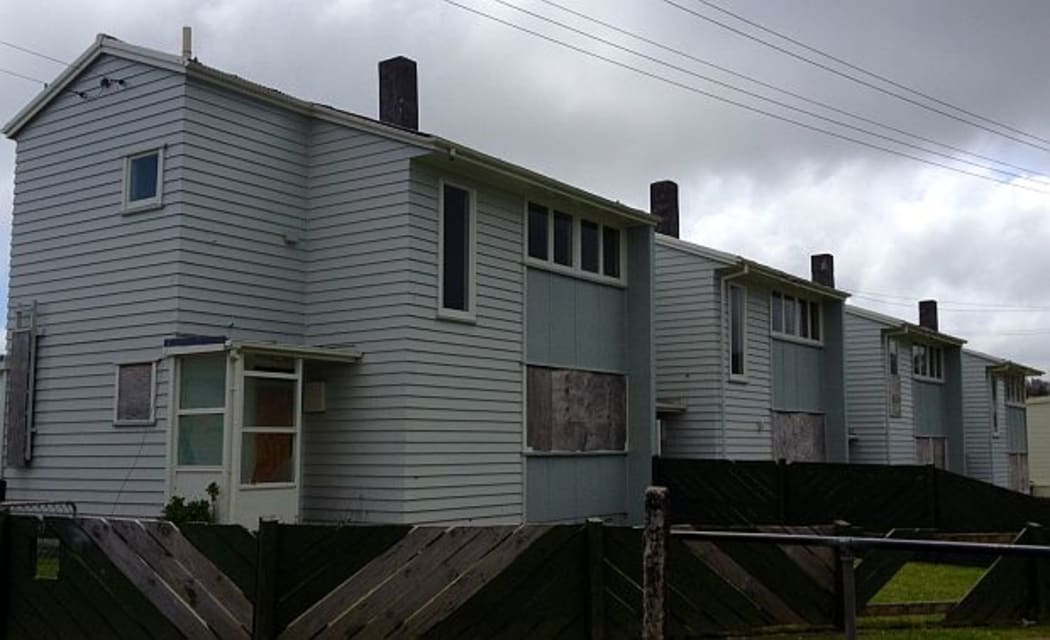 Row of two storey weatherboard houses with boarded up windows