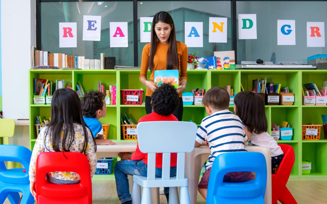Preschool children listening to a teacher read a story