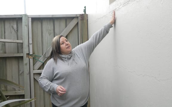 Business owner, Jennifer Rush, examines the patched-up cracks in her shop's exterior walls.