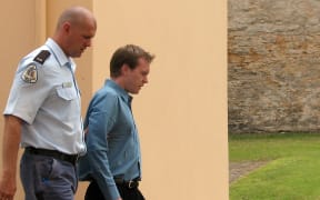New Zealander Glenn McNeill (R), age 29, is led from the cells to the courtroom in the 175-year-old former military barracks in Kingston in the Australian territory of Norfolk Island, 02 February 2007, where he faces a charge of murdering Australian woman Janelle Patton on March 31, 2002.  It is the first murder trial on the island in 150 years since it was settled by the descendants of the British sailors involved in the famous 'Mutiny on the Bounty'.  AFP PHOTO/Lawrence BARTLETT (Photo by LAWRENCE BARTLETT / AFP)