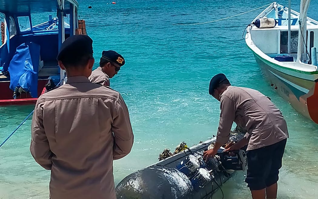 A picture taken on April 6, 2026, shows a torpedo-like 3.7-metre-long and 65-centimetre-wide object, discovered by a fisherman near the Lombok Strait after being towed ashore onto a beach on Gili Trawangan, West Nusa Tenggara. The Indonesian navy said on April 9, it was investigating a torpedo-like object discovered by a fisherman near the Lombok Strait, a key maritime route connecting the Indian and Pacific Oceans. (Photo by AFP)