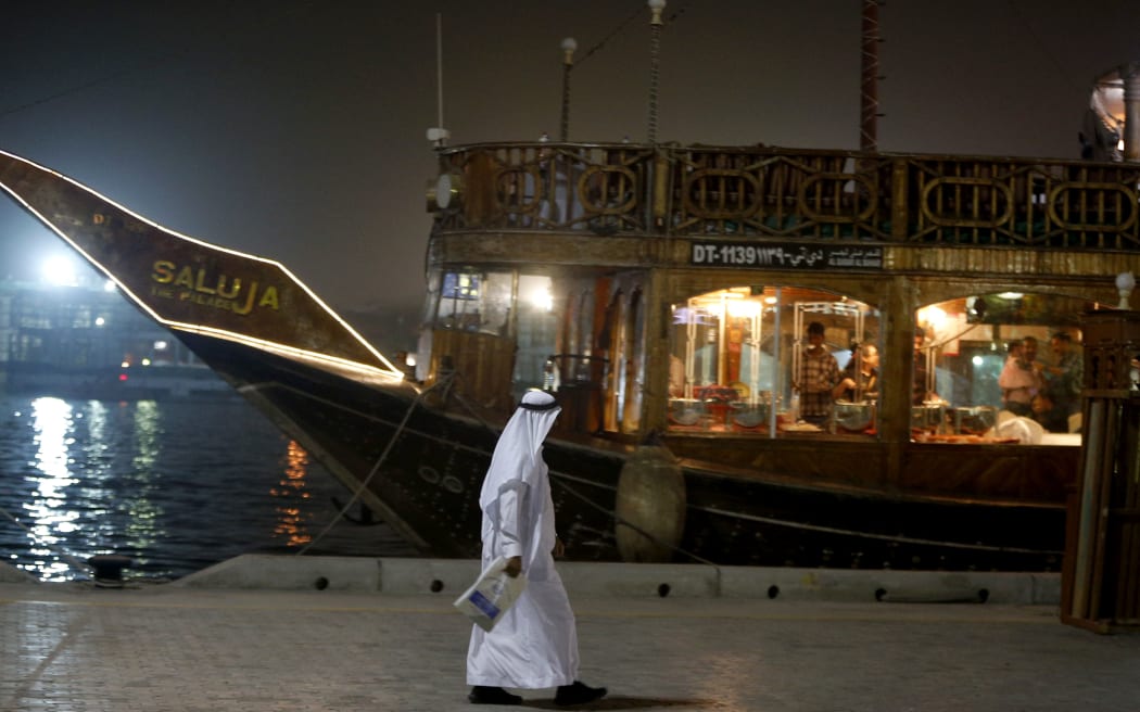 An Emirati man walks past a restaurant boat adorned for the Muslim holy month of Ramadan.