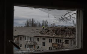 Workers clear debris from the roof of a heavily damaged residential building following a drone strike in Kyiv, on 23 December, 2025, amid the Russian invasion of Ukraine.