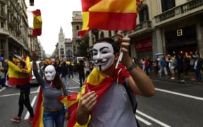 A man wearing a 'Guy Fawkes' mask holds a Spanish flag during a demonstration in Barcelona against independence in Catalonia.