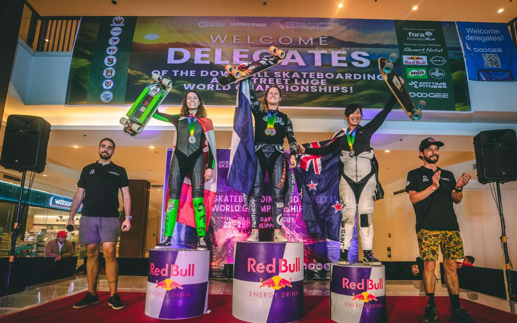 New Zealand's Elissa Mah (r) stands on the podium after finishing third at the 2024 Downhill Skateboarding World Championships.