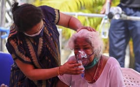 A Covid-19 patient breathes with the help of oxygen provided by a Gurdwara, a place of worship for Sikhs, under a tent installed along a roadside in Ghaziabad on 28 April 2021.