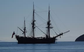 A big three masted sailing ship in the bay.