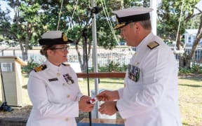 Deputy Chief of Navy, Commodore Shane Arndell, right, hands over the Commissioning Pennant to new HMNZS Philomel Commanding Officer, Commander Julie Simpkins