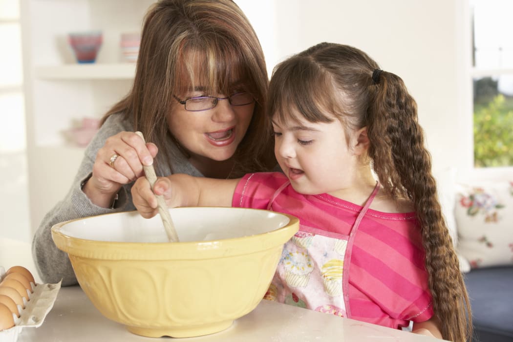 A photo of a girl with downs syndrome baking with mother