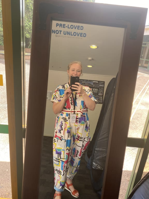 Gently Loved market organiser Donna Buchanan, wearing a colourful jumpsuit, takes a selfie in a mirror.