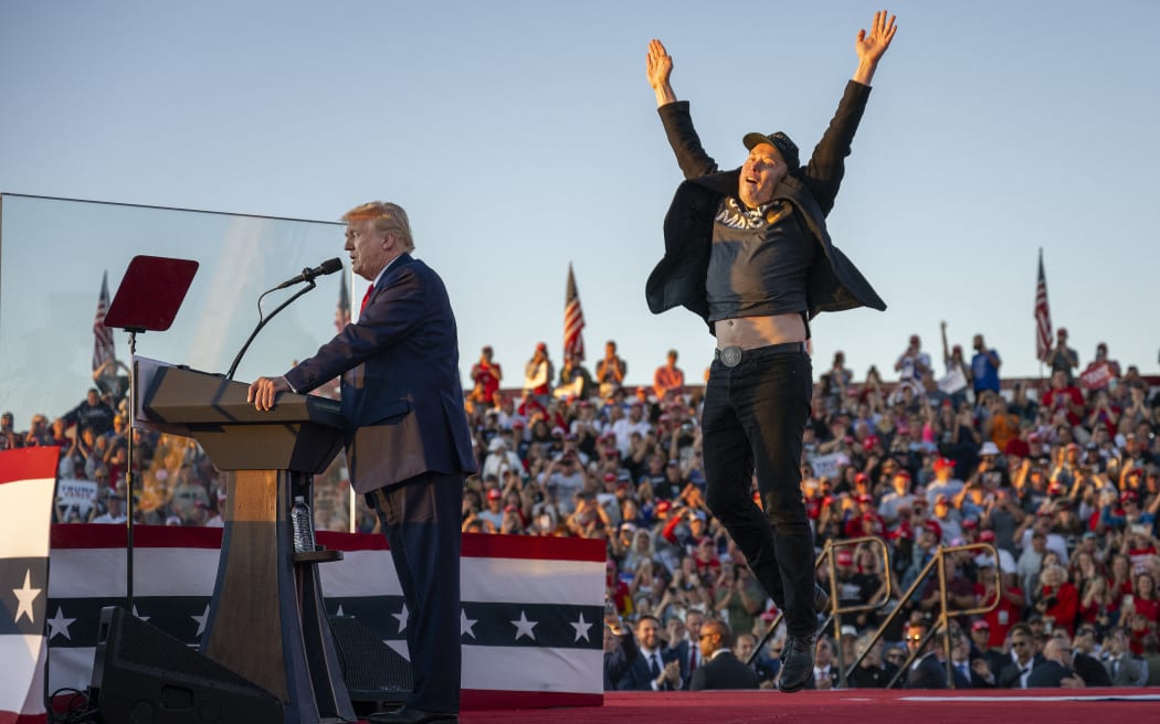 Tesla CEO Elon Musk (R) jumps on stage as he joins former US President and Republican presidential candidate Donald Trump during a campaign rally at site of his first assassination attempt in Butler, Pennsylvania on October 5, 2024. (Photo by Jim WATSON / AFP)