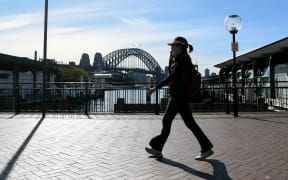 A woman walks along a quiet Circular Quay in Sydney on 6 July 2021, as the city remains in lockdown for a second week to contain an outbreak of the highly contagious Delta Covid-19 variant.