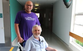 Taranaki Base Hospital orderly supervisor Ocean Falaniko (standing), says Robbie Campbell (sitting) has a beautiful way with patients, often putting a smile on their face during difficult times for them. Campbell has recently racked up 48 years as an orderly.