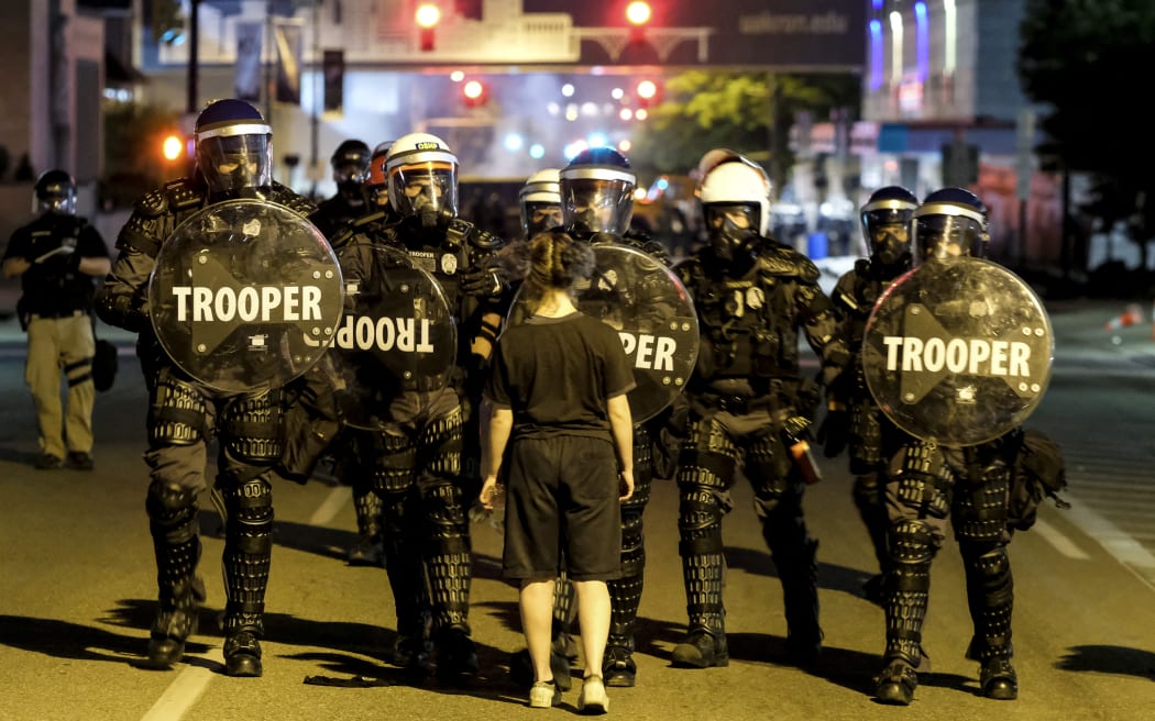 A woman stands in front of troopers in riot gear as police deployed tear gas and stun grenades to clear the area around Akron City Hall and Akron Police Station during a protest over the killing of Jayland Walker, shot by police, in Akron, Ohio, July 3, 2022. - Several hundred protesters marched Sunday in Akron, Ohio after the release of body camera footage that showed police fatally shooting a Black man with several dozen rounds of bullets.
As anger rose over the latest police killing of a Black man in the United States, and authorities appealed for calm, a crowd marched to City Hall carrying banners with slogans such as "Justice for Jayland." (Photo by Matthew Hatcher / AFP)