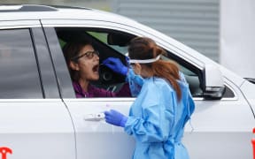 A healthcare worker takes a swab from a patient at a drive-through testing station in Perth on June 29, 2021, as several positive Covid-19 coronavirus cases have led to a four day lockdown of the Perth metropolitan area.
