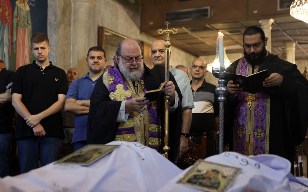 Archbishop Alexios blesses the bodies of Saad Salameh and Foumia Ayyad, killed earlier in an Israeli strike that hit the Holy Family church in Gaza City, during their funeral ceremony at the Saint Porphyrius Church on July 17, 2025. An Israeli strike on Gaza's only Catholic church killed three people on July 17, the Latin Patriarchate of Jerusalem said, as Israel said it "never targets" religious sites and regretted any harm to civilians. (Photo by Omar AL-QATTAA / AFP)