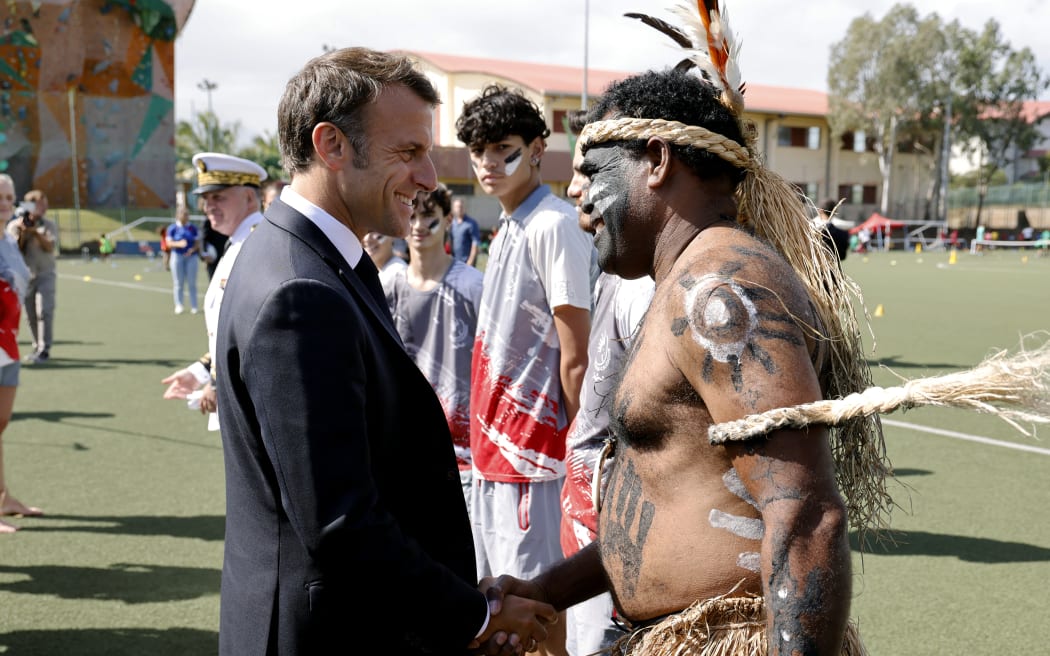 French President Emmanuel Macron shakes hands with a traditional dancer during a visit to the Magenta suburb of Noumea.