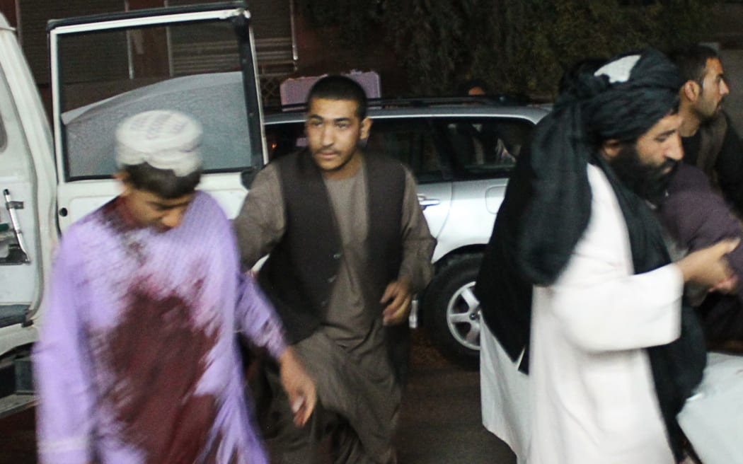 Men carry a wounded man onto a stretcher outside a hospital following a car bomb in Lashkar Gah, the capital of Helmand province, on March 23, 2018.