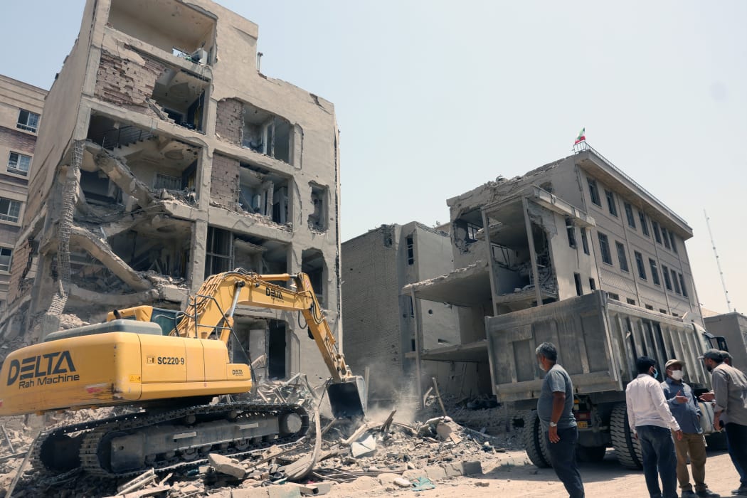 An excavator is used to clear the rubble in front of a building recently hit in Israeli strikes in Tehran on June 26, 2025, following a ceasefire with Israel that ended 12 days of fighting. (Photo by AFP)