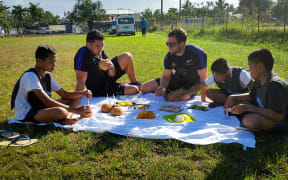 All Blacks Codie Taylor and Tom Taylor share some fruit with local children.