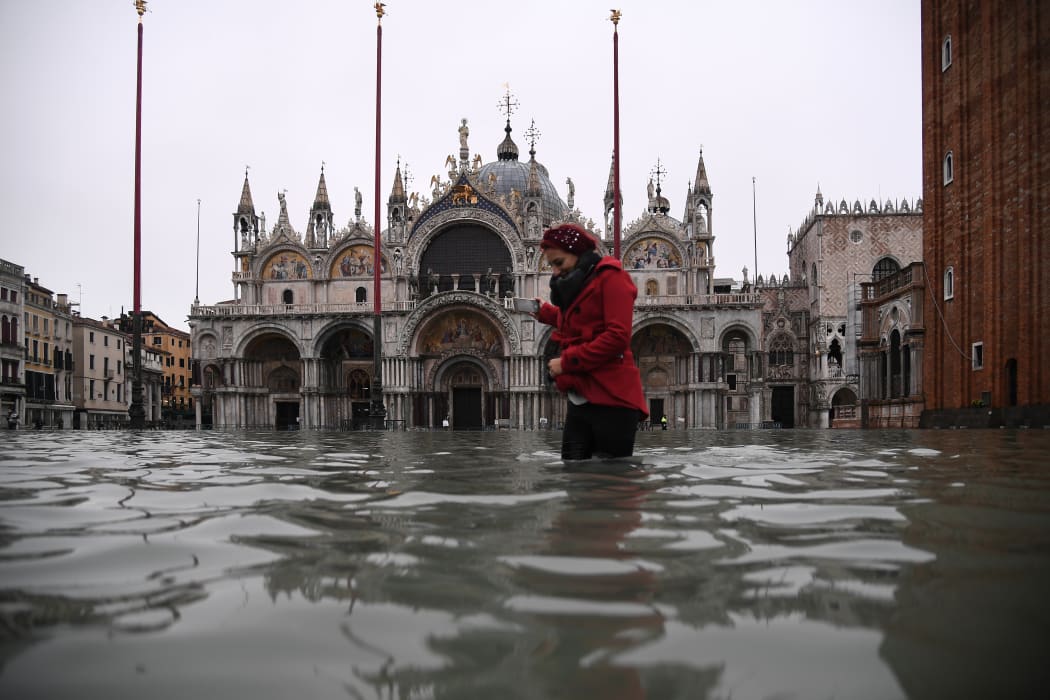 A woman crosses the flooded St. Mark's square by St. Mark's Basilica after an exceptional overnight "Alta Acqua" high tide water level, early on 13 November, 2019 in Venice.