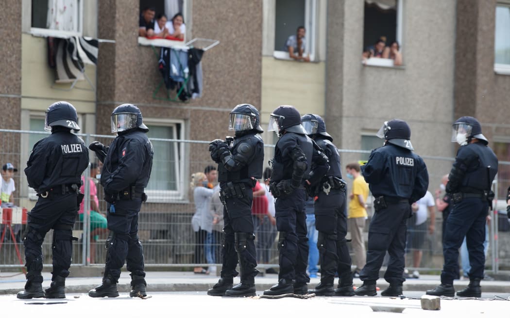 20 June 2020, Lower Saxony, Göttingen: Policemen are standing in front of a quarantined apartment building in downtown Göttingen. Earlier, a demonstration against rent craze took place in front of the building.