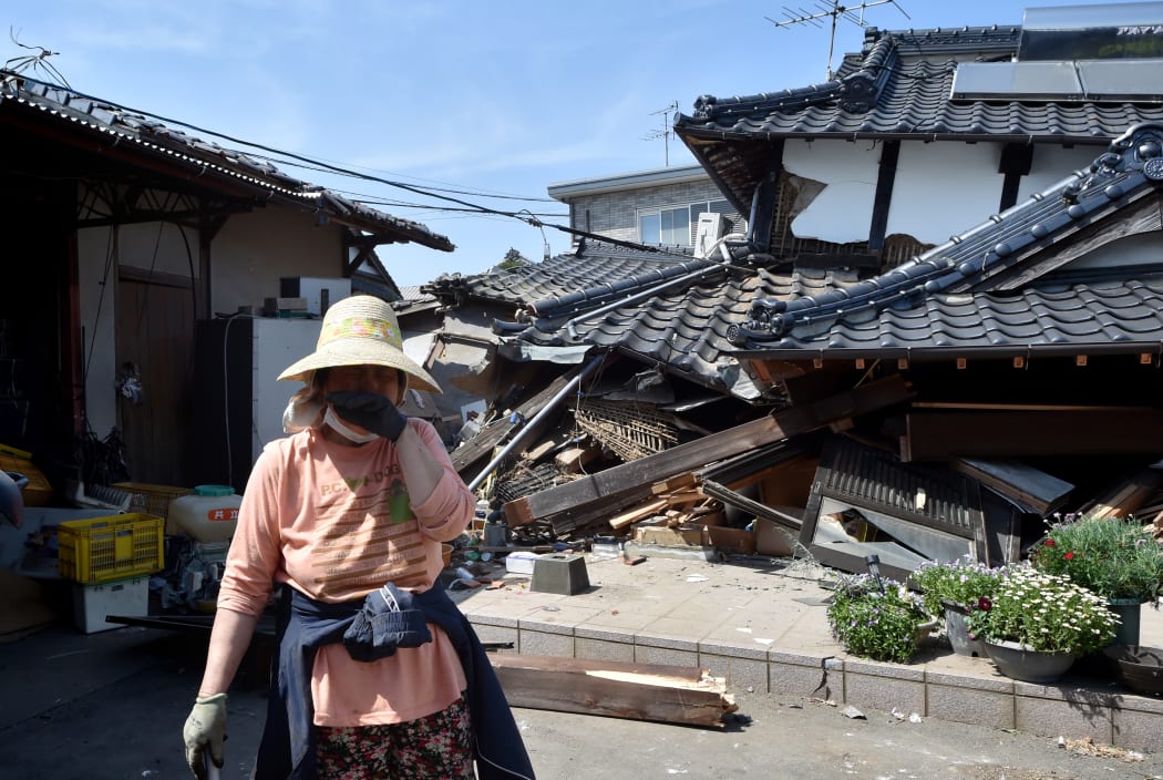 A woman stands in front of her damaged house in Mashiki, Kumamoto prefecture after a 6.5 magnitude quake struck the southwestern island of Kyushu on April 14.