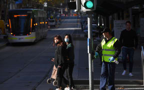 A cleaner wipes down a pole in Melbourne's central business district on June 17, 2020, as more Australians return to the city centre with a relaxing of the COVID-19 coronavirus rules.