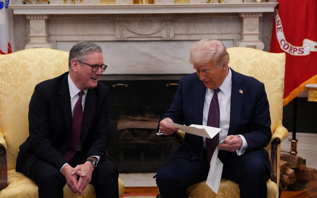 US President Donald Trump reads a letter from Britain's King Charles III handed to him by British Prime Minister Keir Starmer (L) during a meeting in the Oval Office of the White House in Washington, DC, on February 27, 2025. Starmer is meeting Trump to plead for a US backstop to any Ukraine ceasefire, insisting it would be the only way to stop Russia's Vladimir Putin from invading again. Starmer arrived in Washington late Wednesday to build on a visit by French President Emmanuel Macron, amid growing concerns in Europe that the US leader is about to sell Kyiv short in negotiations with Putin. (Photo by Carl Court / POOL / AFP)