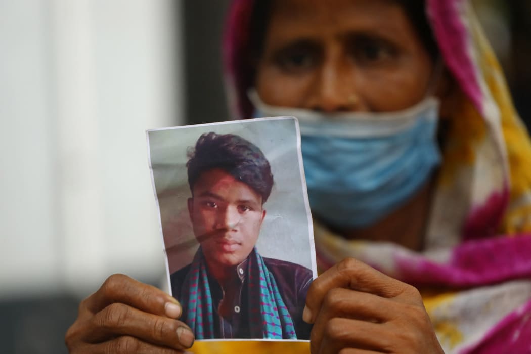 A mother, Jamena, shows a photo of her missing son Naim, 17, at Dhaka Medical College Hospital, she fears he died in the Hashem Foods fire in the outskirts of Dhaka.