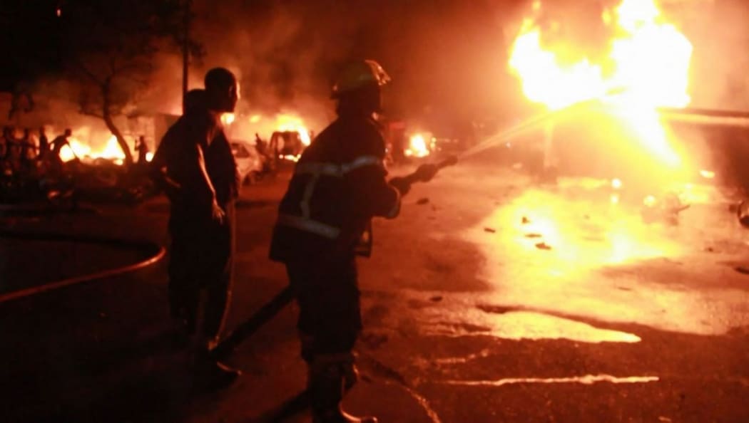 This video frame grab taken from AFPTV footage shows firefighters working to put out a fire at a petrol station early on November 6, 2021 in Freetown, Sierra Leone, following a massive explosion that has killed at least 92 people.