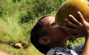 A Tongan child drinks from a coconut near the Tuanekivale medical site for Pacific Partnership 2011.