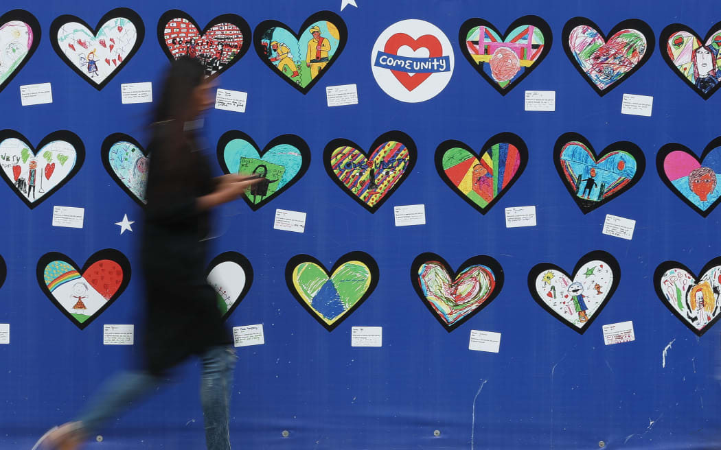 A woman walks past an artwork for the victims of the Grenfell Tower fire