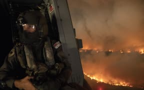This handout photo taken on December 21, 2019 and obtained on December 22 from the Australia Department of Defence shows an aircrewman monitoring the Tianjara fire from a helicopter in the Moreton and Jerrawangala National Park in Moreton.