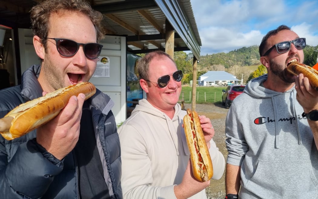 Bratwurst Bros customers (from left) Ben, Chris and Hayden dig into their footlong bratwurst.