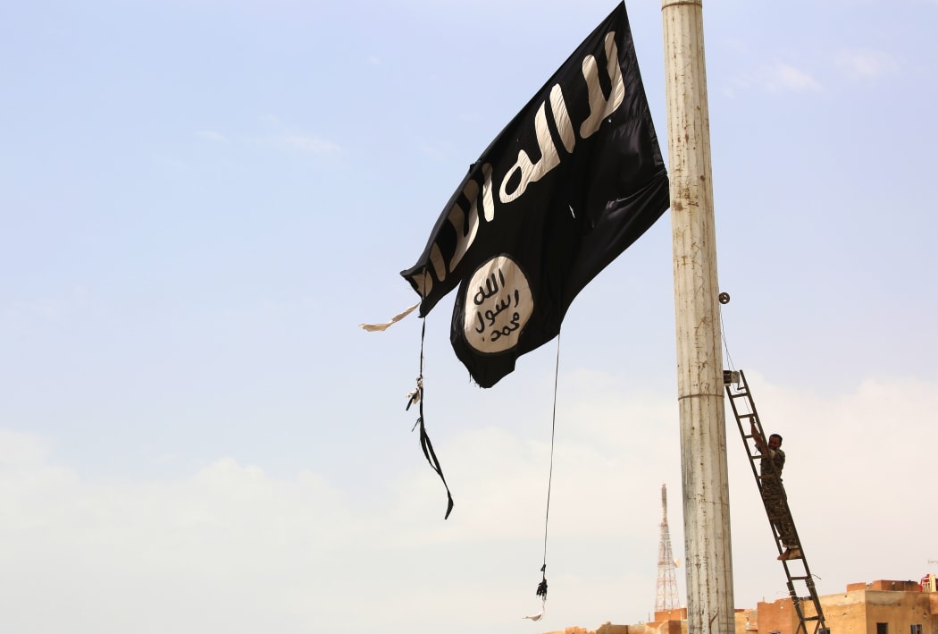 A member of the Syrian Democratic Forces (SDF) removes an Islamic State group flag in the town of Tabqa,  west of Raqa city, as they advance in their battle for the group's de facto capital.