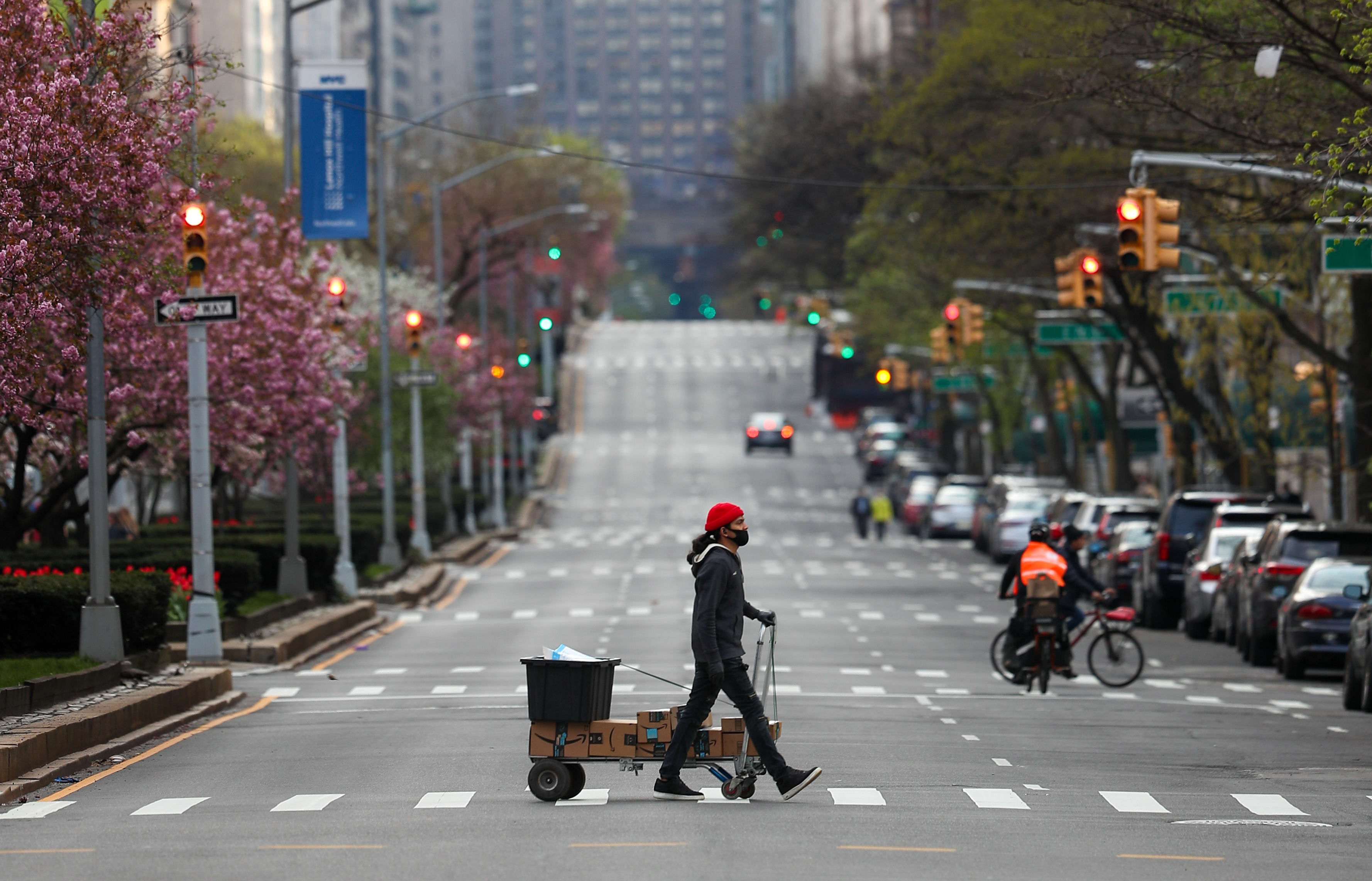 NEW YORK, USA - APRIL 12: An amazon delivery person, with a face mask, crosses a street on Park Avenue, remaining nearly empty due to coronavirus (COVID-19) pandemic in New York City, United States, on April 12, 2020. Tayfun Coskun / Anadolu Agency