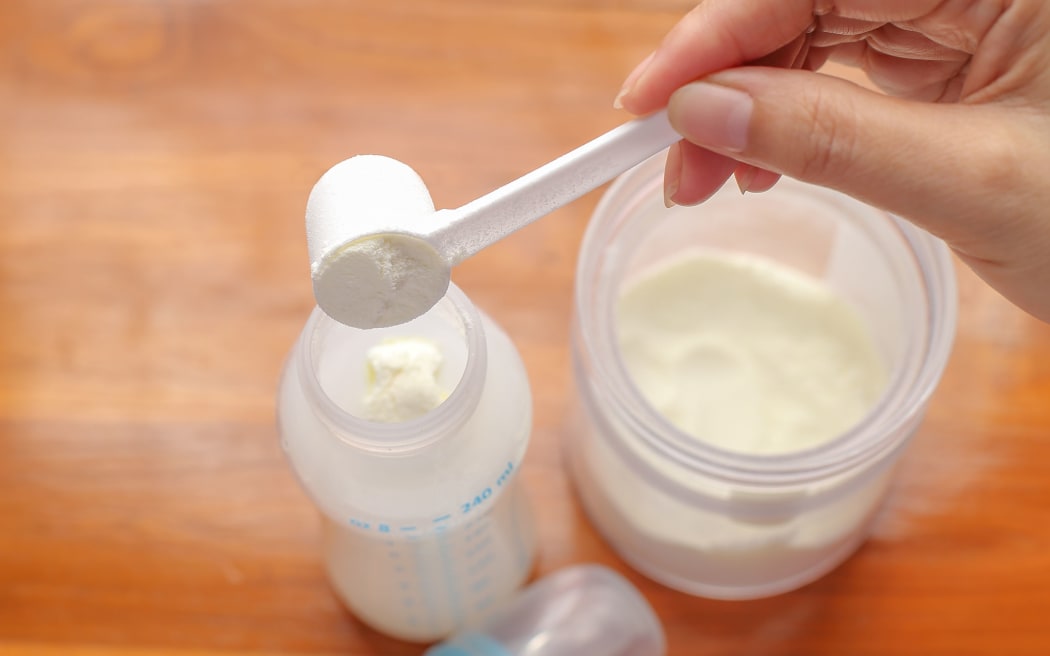 putting powdered milk into a baby bottle