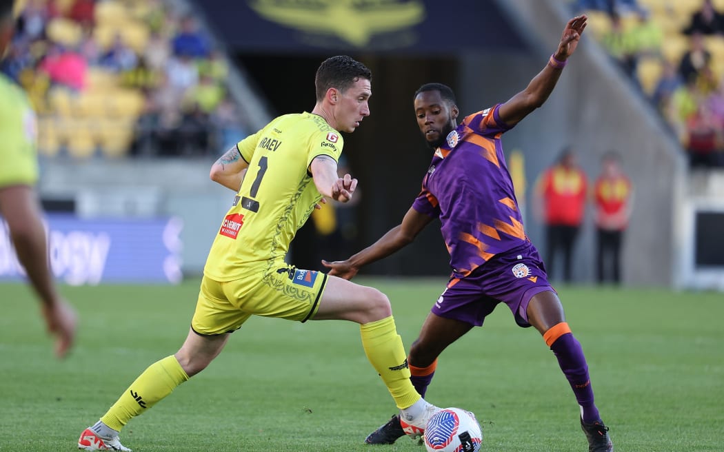 Phoenix player Bozhidar Kraev controls possession against Perth Glory opponent Bruce Kamau during their men's A-League match.