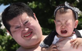 A baby held by a student sumo wrestler cries during a competition at Sensoji Temple in Tokyo on Saturday.