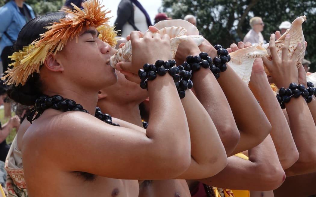 Students of Kamehameha Schools welcome the waka by sounding conch shells.