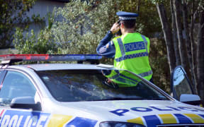 AUCKLAND,NZ - JUNE 03 2014:Traffic Police officer pointing his radar gun at speeding traffic.Traffic Police Monitor traffic to ensure motorists observe traffic regulations and exhibit safe driving procedures.