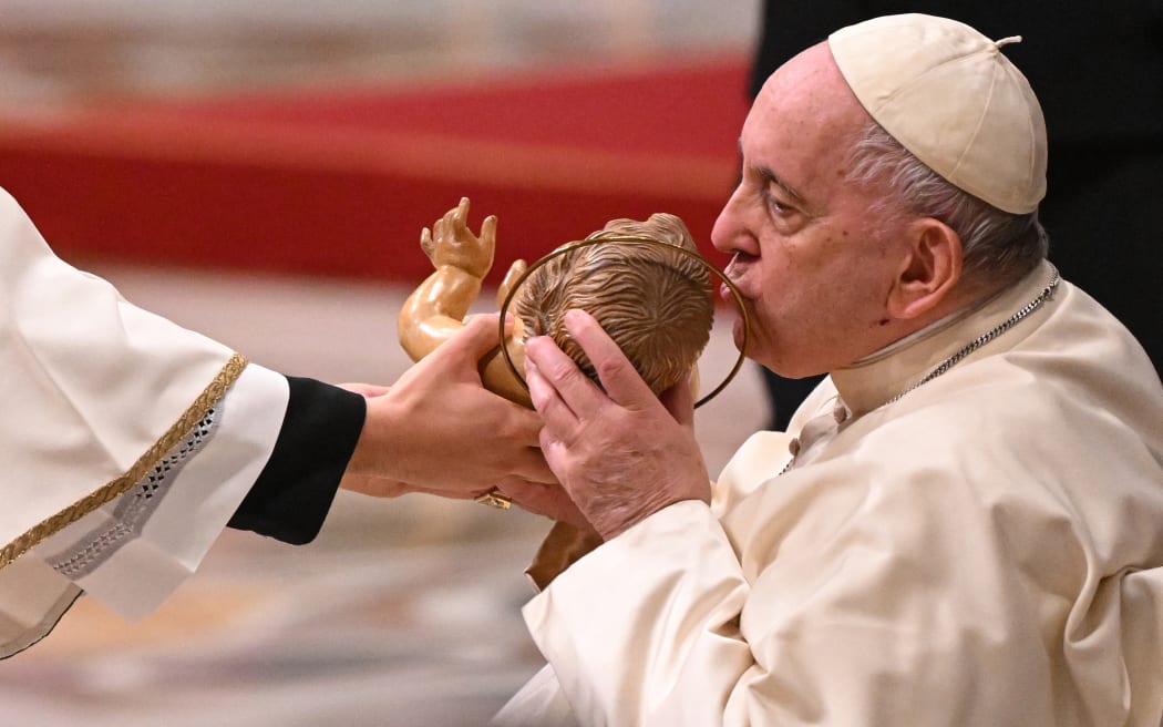 Pope Francis kisses a figurine of baby Jesus as he attends the Christmas Eve mass at The St Peter's Basilica in the Vatican on December 24, 2022. (Photo by Andreas SOLARO / AFP)