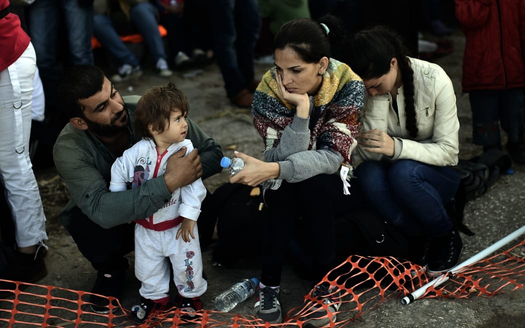 Refugees and migrants rest after arriving at the Greek island of Lesbos after crossing the Aegean sea from Turkey on October 4, 2015. AFP PHOTO / ARIS MESSINIS